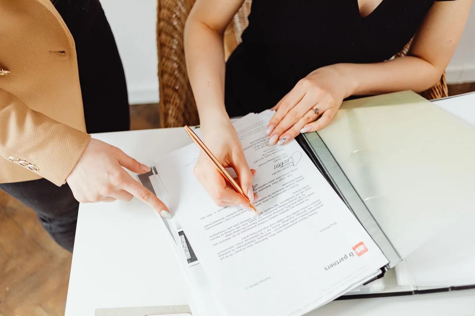 Dos mujeres firmando documentos importantes en un escritorio, mostrando trabajo en equipo.
